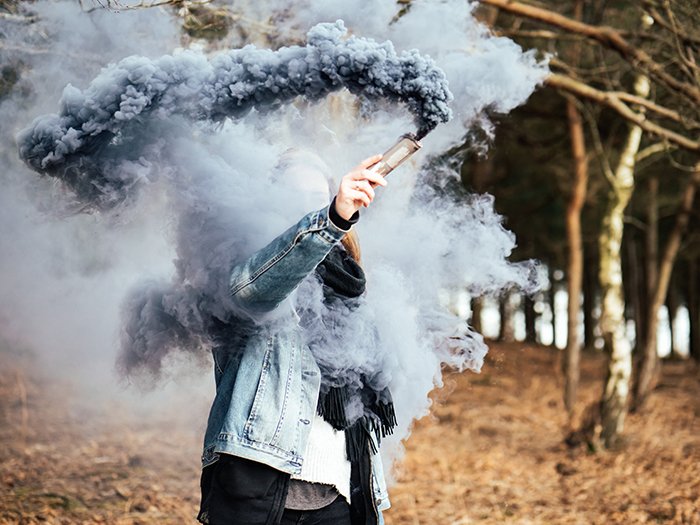 Asmoke bomb photography portrait of a woman holding blue smoke grenade near his face