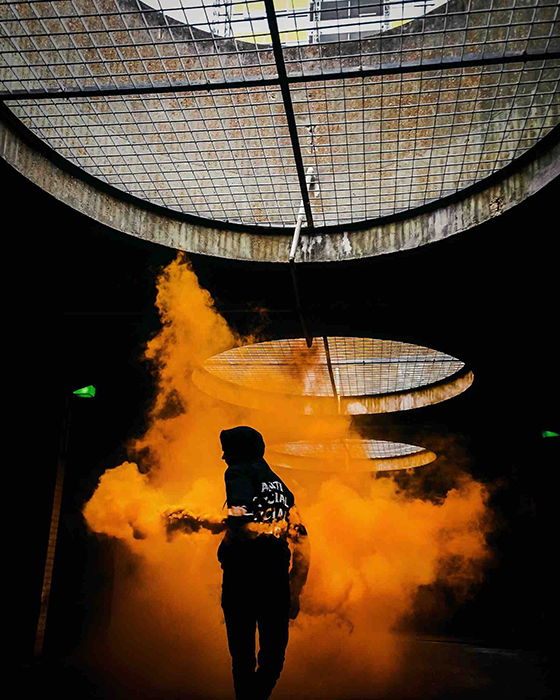 Faceless portrait of a woman holding orange smoke grenades