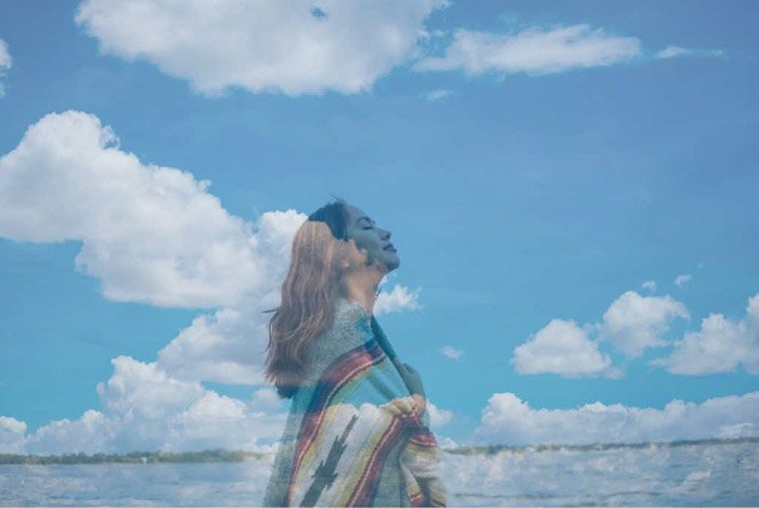 Dreamy photo of a girl superimposed with an image of fluffy clouds 