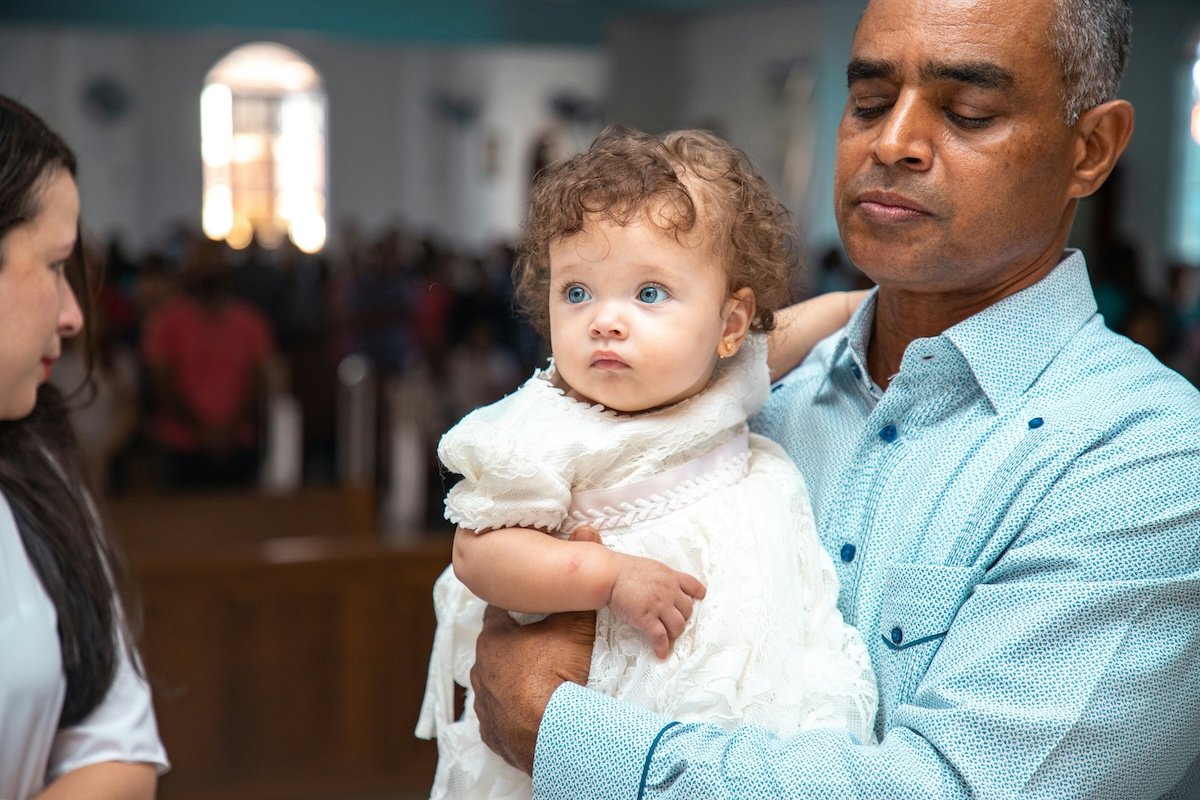 A baby being held for a baptism in a church showing an imbalanced composition