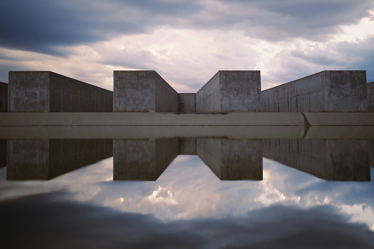A concrete block structure and cloudy sky with water reflections showing balance in photography