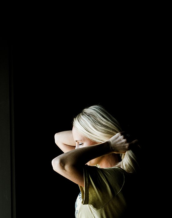 Atmospheric portrait of a female model holding her hair, shot with chiaroscuro lighting