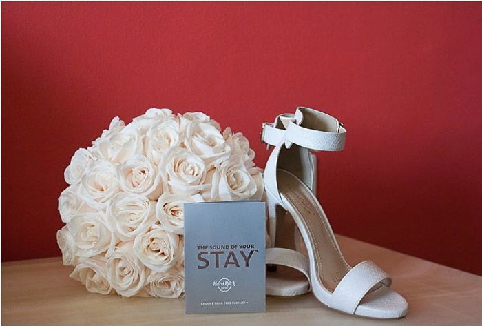 A wedding photography still life featuring a pair of shoes, flowers and booklet