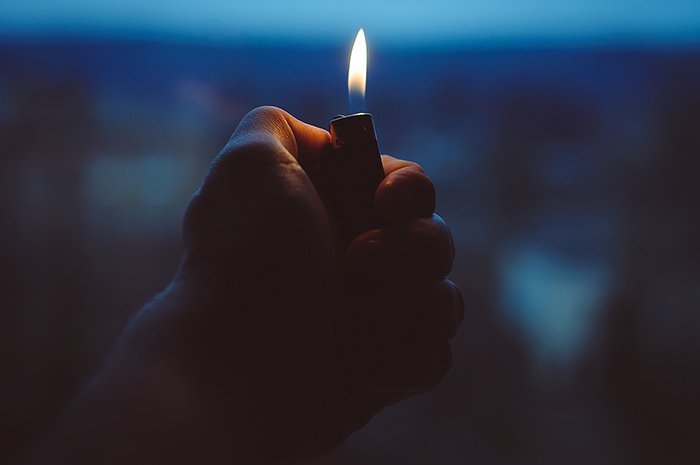 A hand holding a lighter at night