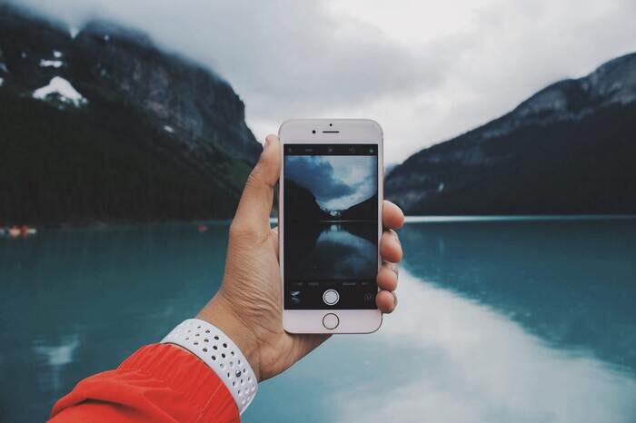 Photo of someone taking a photo with an iphone of a lake