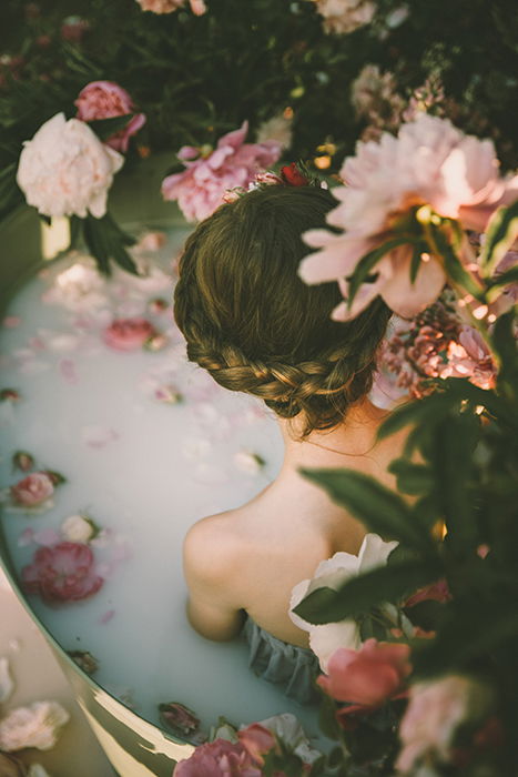 Beautiful milk bath photography of a female model surrounded by flowers