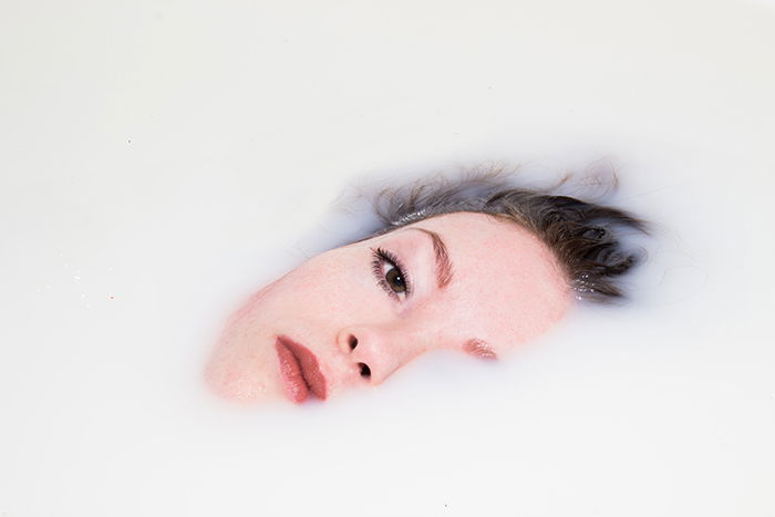 A close up Milk bath photography portrait of a female model submerged in milk