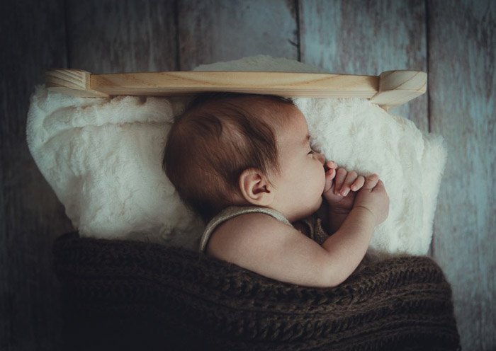 A portrait of a newborn in a small bed 