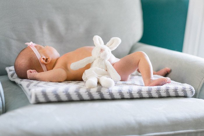 A newborn baby posed on a teddy bear rug 