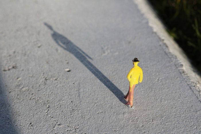 A yellow toy figure on a concrete surface