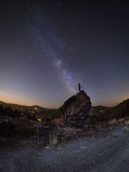 A man on a rock under the Milky Way.