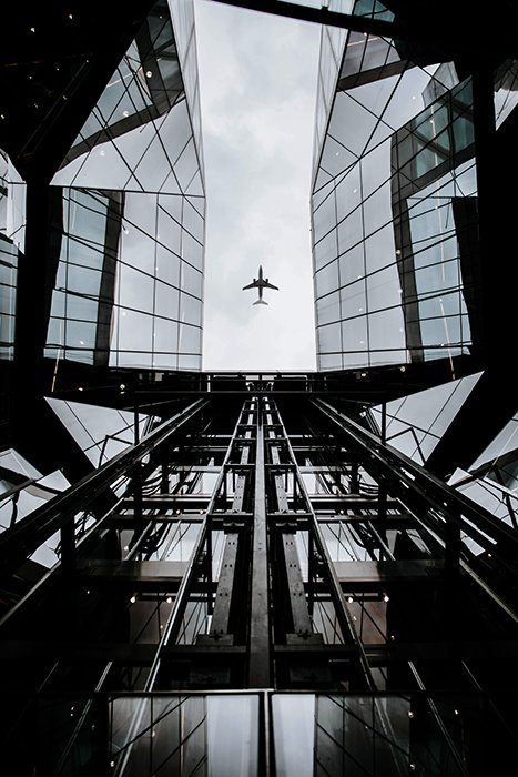 Interesting composition of an airplane framed by a multilayered glass building 
