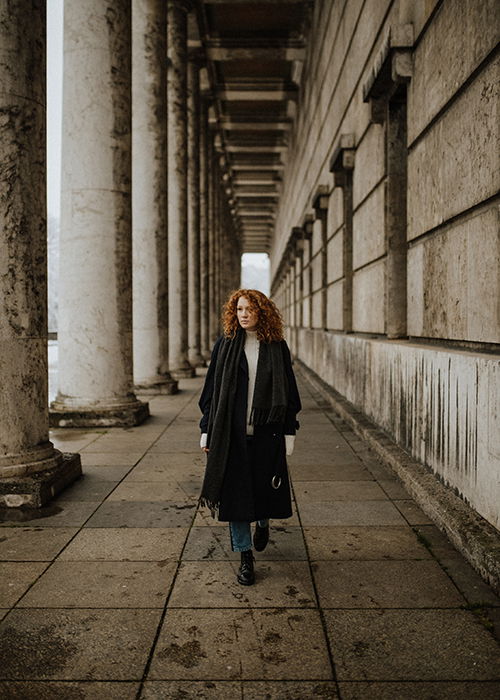 A portrait of a woman walking through a stone pathway using symmetry in photography composition