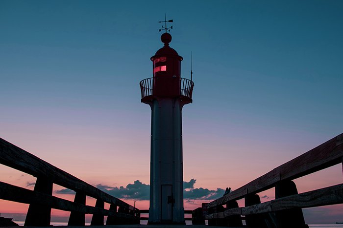 A symmetrical photo of a lighthouse at evening time