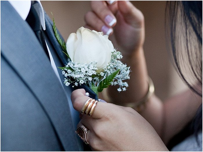Close up prom photography of a cute couple pinning a corsage onto a suit