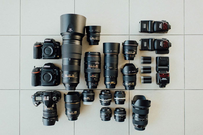 A photography flat lay of camera bodies, flashes and lenses