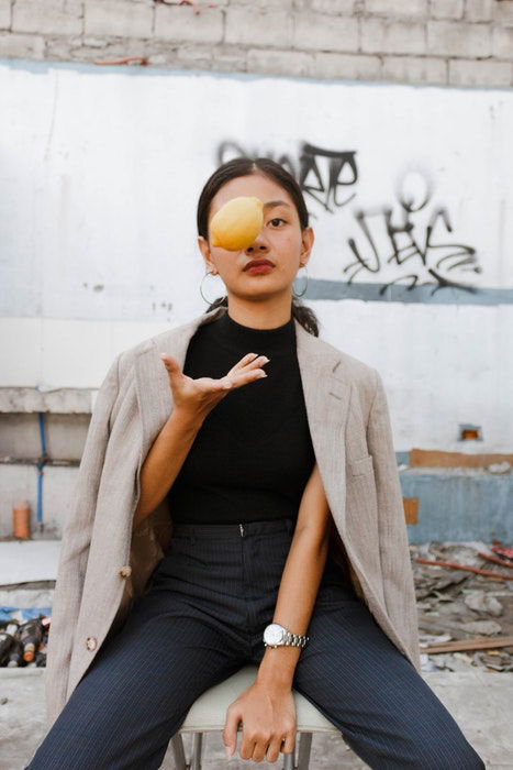 Woman throwing a lemon in the air, looking towards the camera in a casual pose