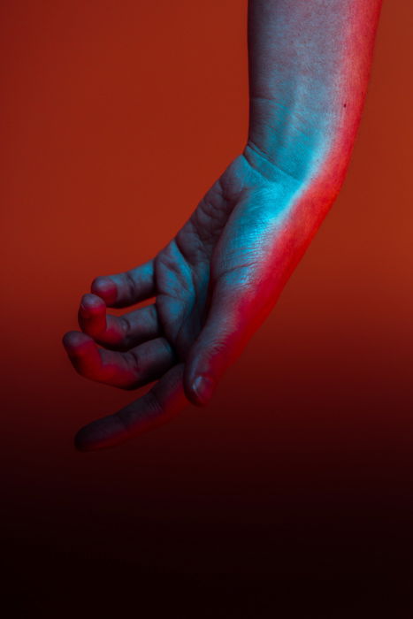 A blue and red toned hand against a red background 