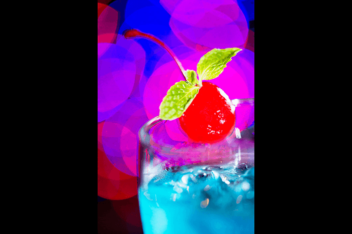 A zoomed-in shot of a blue cocktail with blurry bokeh light background