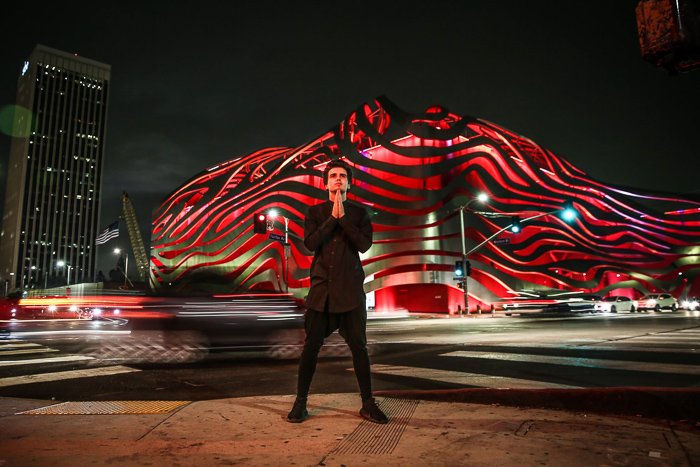 A male model posing in front of an interesting building for an atmospheric night portrait photography shot