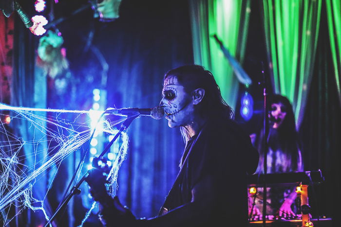 A Gothic male performer onstage in low light - nightclub photography settings 