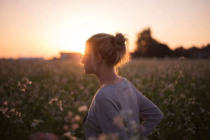 A candid portrait of a female model in a meadow at sunset