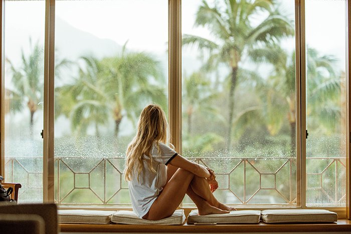 A candid lifestyle shot of a female model looking out a window 