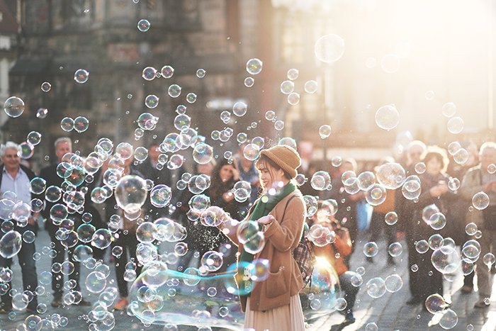 A street photography shot of a woman playing with bubbles outdoors 