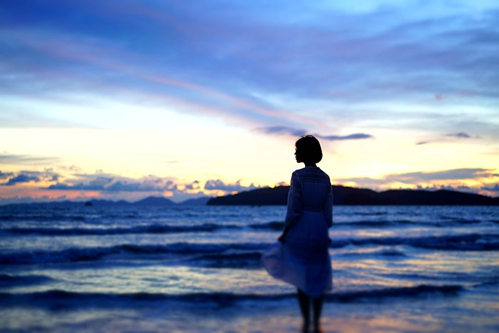A candid photography example of of a woman on a beach at night 