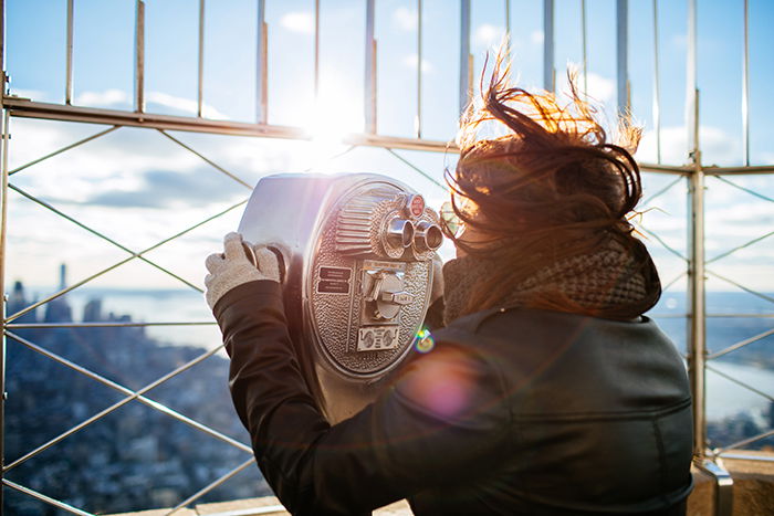 A tourist looking through coin operated binoculars at a viewpoint