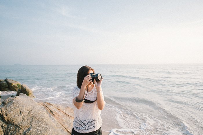 A candid photography example of a woman taking photos on the beach
