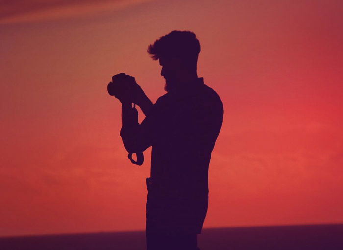 The silhouette of a photographer against a stunning orange sky