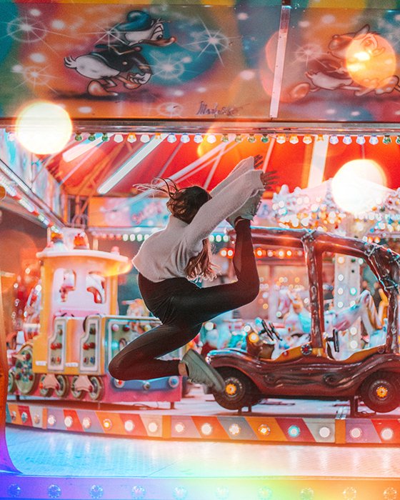 A female dancer in mid air in front of a carousel