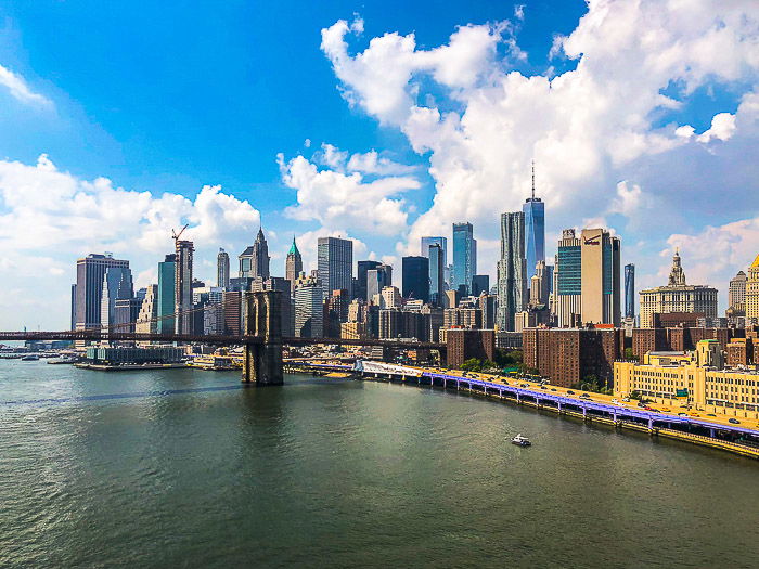 A coastal cityscape under fluffy white clouds and blue sky photography