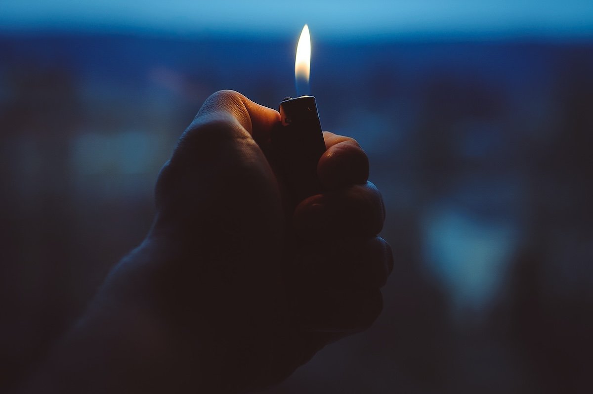 A hand holding a lighter at night for fire photography