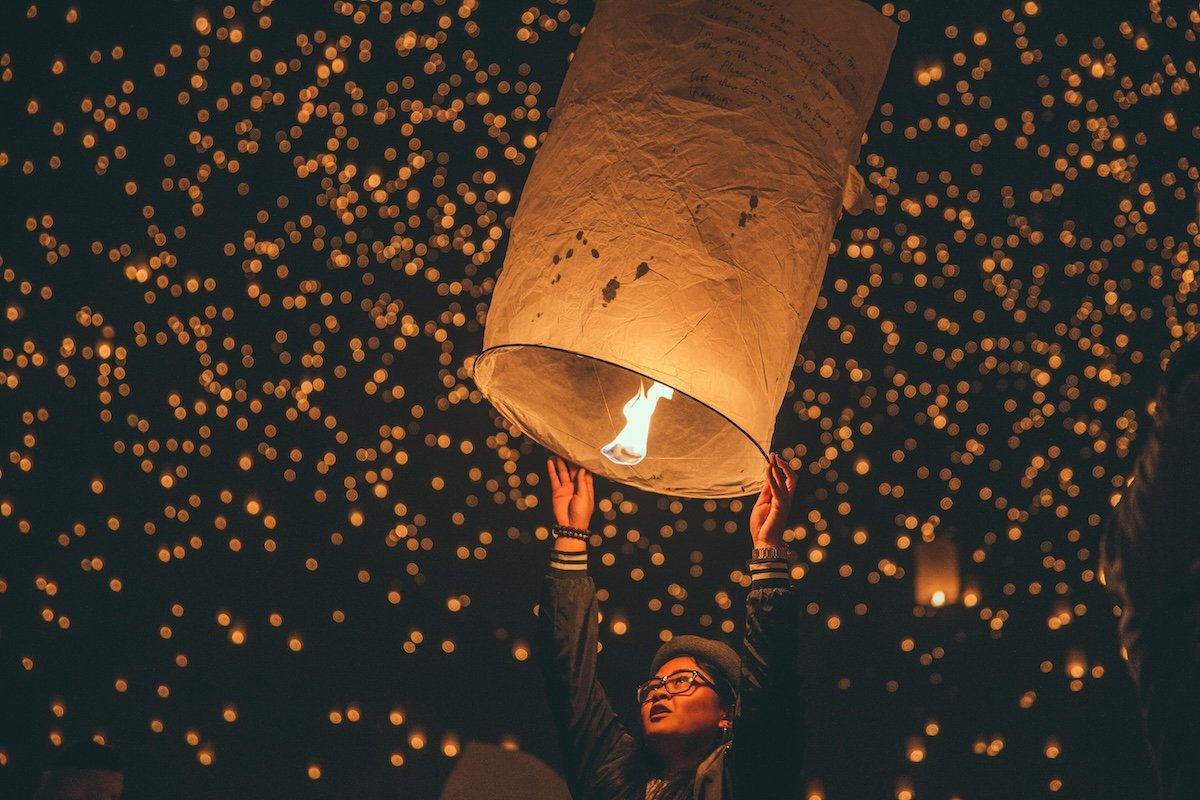 A person holding a lantern up at a festival for fire photography