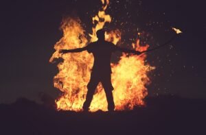 A person standing in front of a large bonfire creating a silhouette for fire photography