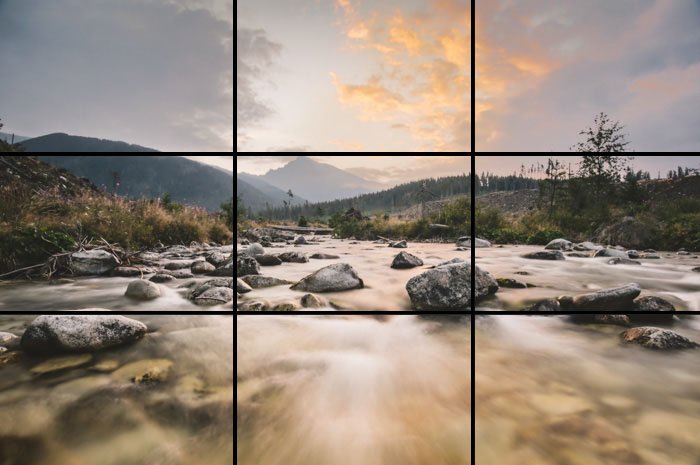 A landscape scene focusing on a soft misty flowing river with the rule of thirds grid overlayed