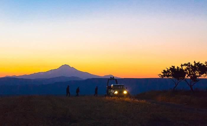 A mountains evening landscape with the silhouettes of photographers preparing to take hot air balloon photos