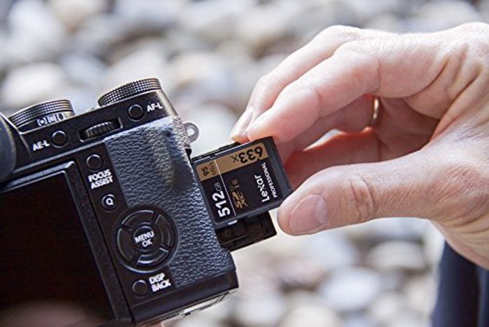 A close up of a person putting a sd card into the camera slot - memory cards types