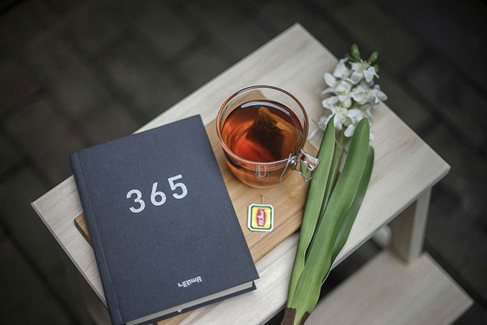 A still life with a book, cup of tea and flower on a table