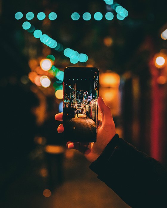 A person taking a photo of a street at night using a smartphone - photography challenges