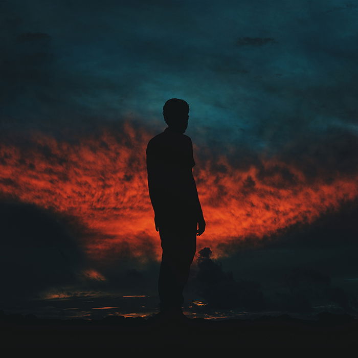 The silhouette of a man against a fiery sky at night - photography assignments