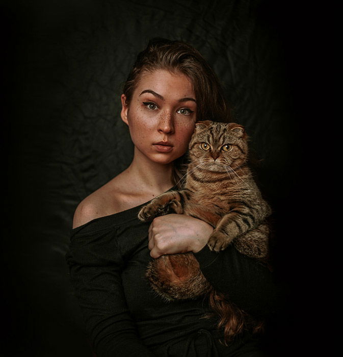 Atmospheric portrait of a female model holding a brown cat 