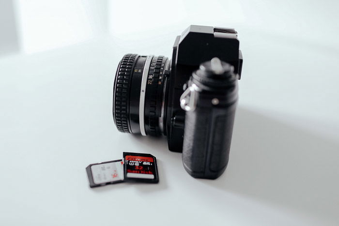 A camera beside two memory cards on white background