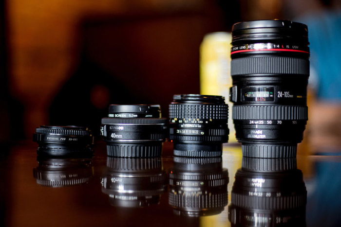 Four different camera lenses on a glass table