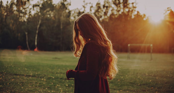 Dreamy portrait of a female model posing in a park during golden hour