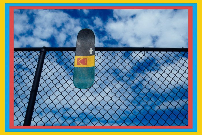 A skateboard resting on a wire fence with a colored border - Photoshop frames