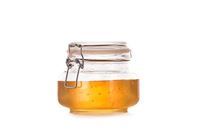 A product photography shot of a jar of honey on white background
