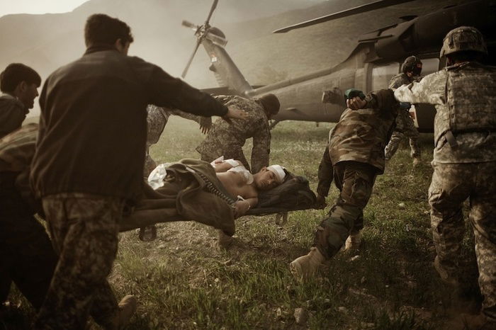 Soldiers helping injured people towards a helicopter by Moises Saman